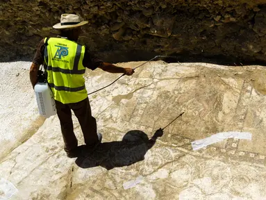 Seorang Arkeolog membersihkan mosaik peninggalan Romawi di Larnaca, Siprus (14/7). Saat ditemukan, Mosaik langka ini sebesar 15 meter dan terkubur di bawah tanah. (Iakovos Hatzistavrou / AFP)