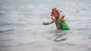 Seorang pria berpakaian seperti Dewa Laut berendam di laut saat melakukan ritual di pantai desa Fuye, Provinsi Fujian, Tiongkok (5/3). (AFP Photo/Johannes Eisele)