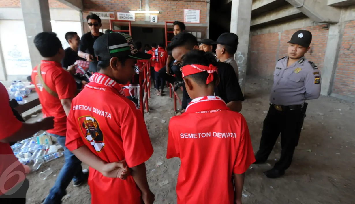 Petugas kepolisian mengawasi proses pemeriksaan suporter di depan pintu masuk Stadion I Wayan Dipta, Gianyar, Bali, Minggu (30/8/2015). Jelang pembukaan turnamen Piala Presiden 2015, ribuan suporter menyerbu stadion. (Liputan6.com/Helmi Fithriansyah) 