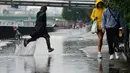 Orang-orang berlarian di tengah hujan di London, Rabu (17/8/2022). Setelah berminggu-minggu cuaca terik, yang telah menyebabkan kekeringan dan membuat tanah kering, peringatan badai petir kuning dari Kantor Meteorologi memperkirakan hujan lebat dan badai petir yang bisa melanda bagian Inggris dan Wales. (Victoria Jones/PA via AP)