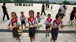 Anak-anak membawa bunga saat akan memberi penghormatan kepada patung pemimpin Korea Utara Kim Il Sung dan Kim Jong Il dalam peringatan berakhirnya Perang Dunia II dan pembebasan dari kolonial Jepang di Pyongyang, Korut, Rabu (15/8). (AP Photo/Ng Han Guan)