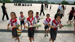 Anak-anak membawa bunga saat akan memberi penghormatan kepada patung pemimpin Korea Utara Kim Il Sung dan Kim Jong Il dalam peringatan berakhirnya Perang Dunia II dan pembebasan dari kolonial Jepang di Pyongyang, Korut, Rabu (15/8). (AP Photo/Ng Han Guan)