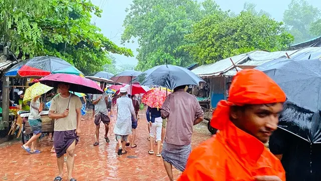 Warga berjalan di tengah guyuran hujan di kamp pengungsi Rohingya di Cox’s Bazar, Bangladesh, pada Selasa (7/72026).