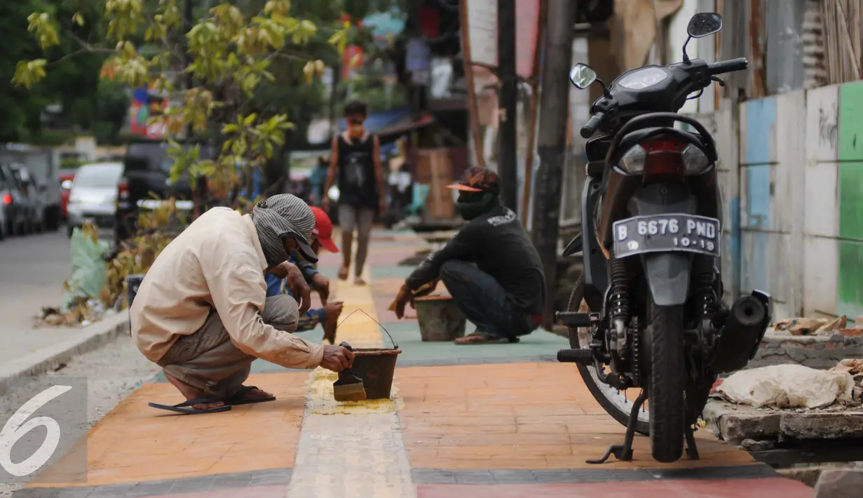 Para pekerja menyelesaikan pembangunan Trotoar Ramah Disabilitas di Jalan Hidup Baru, Kalimati, Jakarta Utara, Selasa (27/12). (Liputan6.com/Gempur M. Surya)