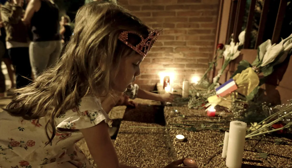 Seorang gadis cilik meletakkan sebuah lilin didepan kedutaan besar Perancis di Paraguay, Sabtu  (14/11/2015).  Ini sebagai  duka cita terhadap ratusan korban akibat serangan di Paris. (REUTERS/Jorge Adorno)