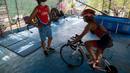 Atlet triathlon Kuba, Leslie Amat mengendarai sepedanya, diadaptasi menjadi stasioner, di bawah pengawasan pelatihnya Dioseles Fernandez di teras rumahnya di Havana, Senin (20/4/2020). Atlet Kuba tak bisa berlatih di fasilitas olahraga seperti biasanya selama pademi corona. (AP /Ismael Francisco)