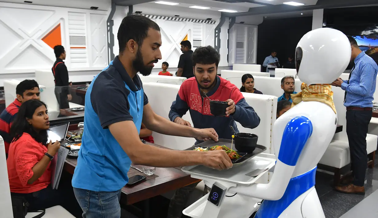 Sebuah robot mengantarkan pesanan makanan kepada pelanggan saat pembukaan restoran di Bangalore, India, Sabtu (17/8/2019). Restoran tersebut memperkenalkan satu robot pengantar serta lima robot untuk berinteraksi dan menyajikan makanan bagi para pelanggannya. (Manjunath Kiran/AFP)