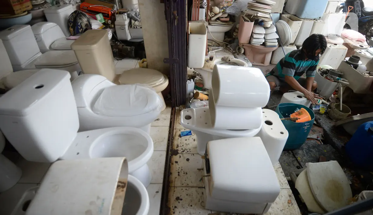 Penjual membersihkan kloset duduk bekas di Jalan Raya Ciater, Serpong, Tangerang Selatan, Banten, Jumat (13/11/2020). Kloset duduk bekas tersebut dijual dengan harga  Rp 500 ribu hingga Rp 1,5 juta pada masa pandemi Kloset bekas banyak diminati pembeli. (merdeka.com/Dwi Narwoko)