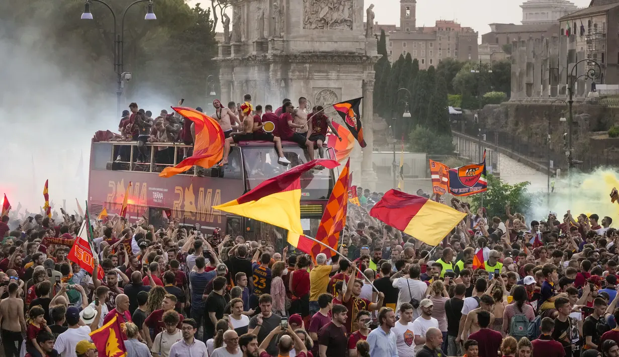 Suporter AS Roma bergembira saat bus membawa pemain AS Roma merayakan kemenangan juara Liga Konferensi Eropa UECL di depan Colosseum di Roma (26/5/2022). AS Roma menjuarai Konferensi Eropa UECL setelah mengalahkan Fayenoord dengan skor tipis 1-0. (AP Photo/Gregorio Borgia)