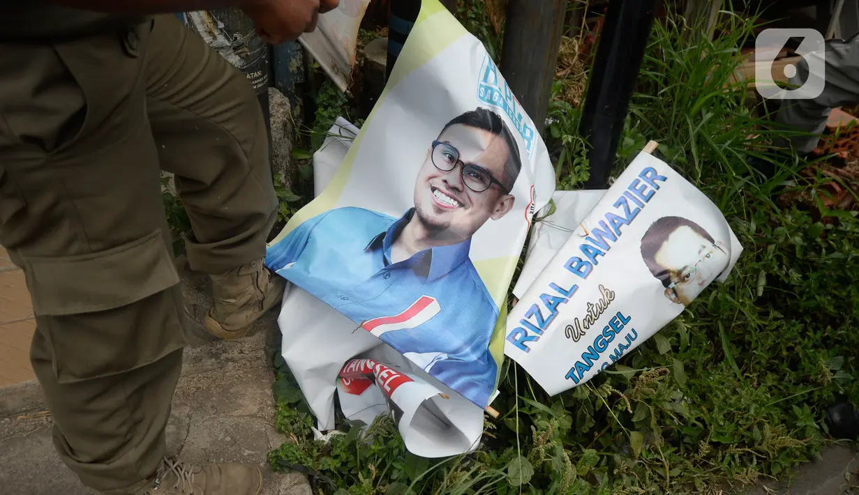 Petugas Satpol PP menertibkan Alat Peraga Kampanye (APK) bakal calon Wali Kota dan Wakil Wali Kota Tangerang Selatan di sepanjang jalan raya di Kota Tangerang Selatan, Kamis (27/8/2020). Semua poster dan baliho diturunkan karena tidak memiliki izin dan masa izin telah habis. (merdeka.com/Dwi Narwoko