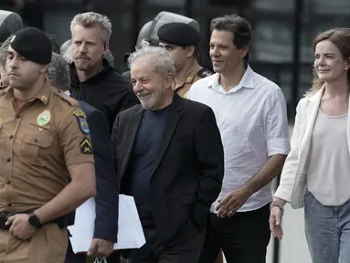 Mantan Presiden Brasil Luiz Inacio Lula da Silva (tengah) tersenyum ketika berjalan keluar dari markas Polisi Federal setelah dipenjara atas tuduhan korupsi di Curitiba, Brasil, (8/11/2019). Luiz Inácio Lula da Silva telah dibebaskan setelah lebih dari 18 bulan dipenjara. (AP Photo/Leo Correa)