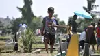 Seorang anak membawa sapu lidi dan botol kosong usai membersihkan salah satu makam di TPU Penggilingan, Pulogadung, Jakarta, Kamis (10/5). Tradisi ziarah jelang Ramadan menjadi berkah bagi anak-anak pembersih makam. (Merdeka.com/Iqbal S. Nugroho)