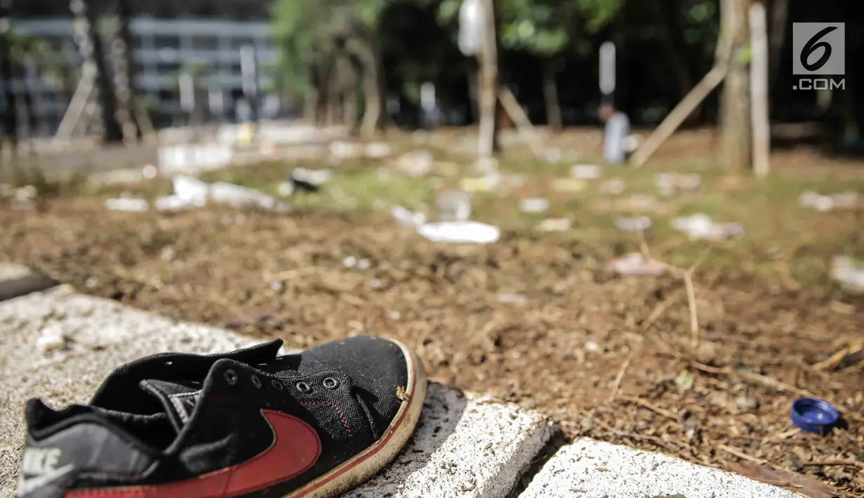 Sepatu terlihat di antara sisa sampah bekas pertandingan Final Piala Presiden 2018 di area Stadion Utama Gelora Bung Karno, Jakarta, Senin (19/10). Sampah-sampah itu ditinggalkan para suporter Persija Jakarta dan Bali United. (Liputan6.com/Faizal Fanani)