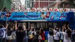 Anggota delegasi Olimpiade Hong Kong mengibarkan bendera selama parade bus, setelah Olimpiade Tokyo 2020, di Hong Kong, Kamis (19/8/2021). Hong Kong yang memiliki 46 atlet perwakilan pada Olimpiade Tokyo 2020 berhasil mengumpulkan satu emas, dua perak dan tiga perunggu. (ISAAC LAWRENCE/AFP)