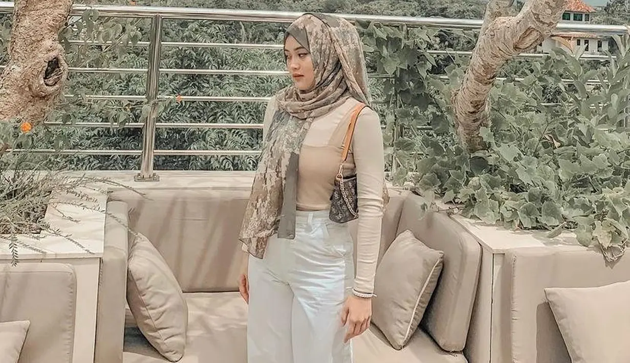Mengenakan longsleeve warna cream dengan celana kulot warna putih. Ia juga memadukannya dengan pashmina motif warna hijau. (Instagram/putridelinaa).