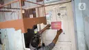 Warga memantau rumah warga yang sedang isolasi madiri di zona merah COVID-19 Kelurahan Petogogan RT 006 RW 003, Jakarta, Selasa (22/6/2021). Pemerintah Provinsi DKI Jakarta memperbarui data zona pengendalian virus Corona di tingkat rukun tetangga (RT) se-Ibu Kota.  (Liputan6.com/Faizal Fanani)