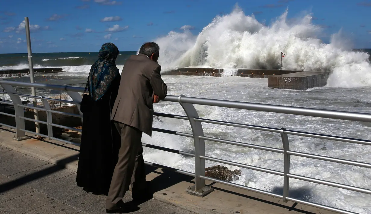 Pasangan suami istri melihat terjangan ombak di dinding laut Fishers Marina, di tepi pantai Corniche, atau promenade tepi laut, di Beirut, Lebanon (26/10). (AP Photo / Hussein Malla)