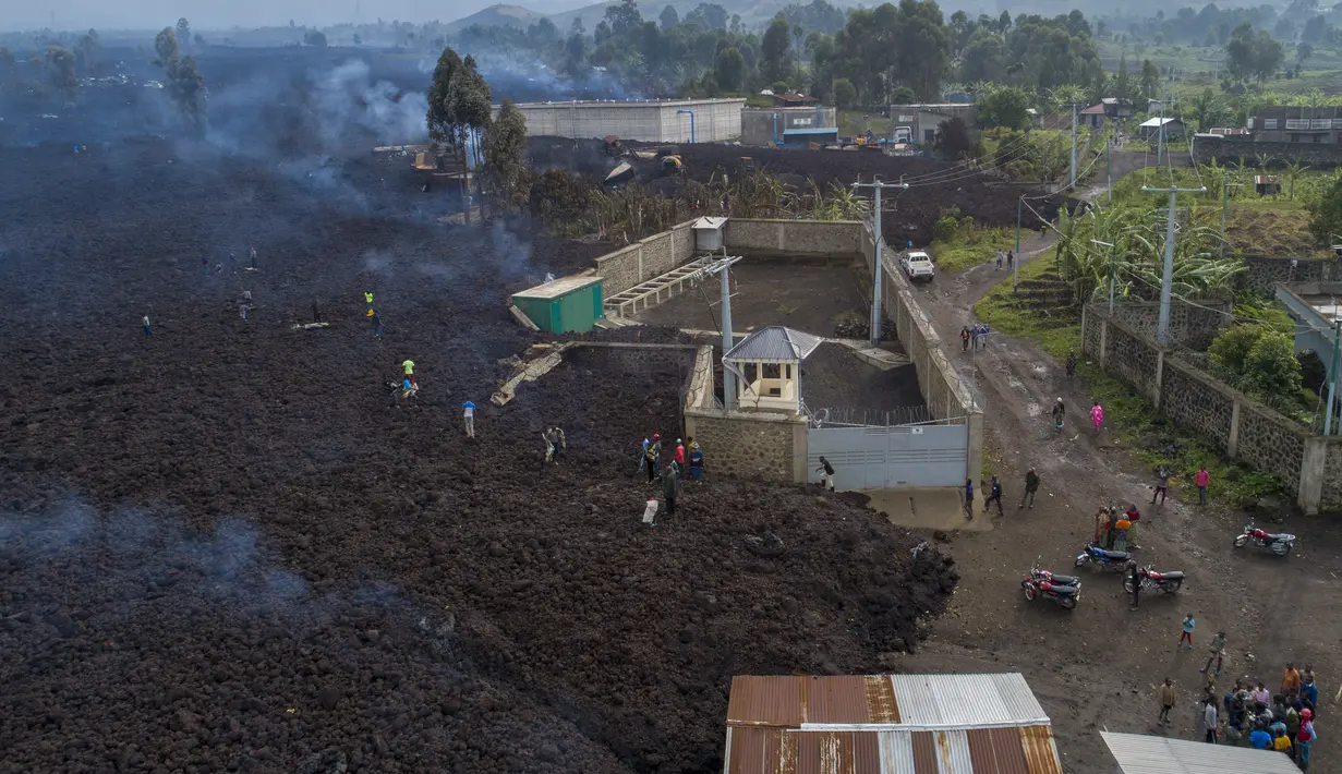 Warga melihat lava dari letusan Gunung Nyiragongo membelah Buhene di utara Goma, Kongo (24/5/2021). Gunung Nyiragongo mengirimkan aliran lahar ke desa-desa smenyebabkan sedikitnya 15 orang tewas di tengah kekacauan dan menghancurkan lebih dari 500 rumah. (AP Photo/Justin Kabumba)