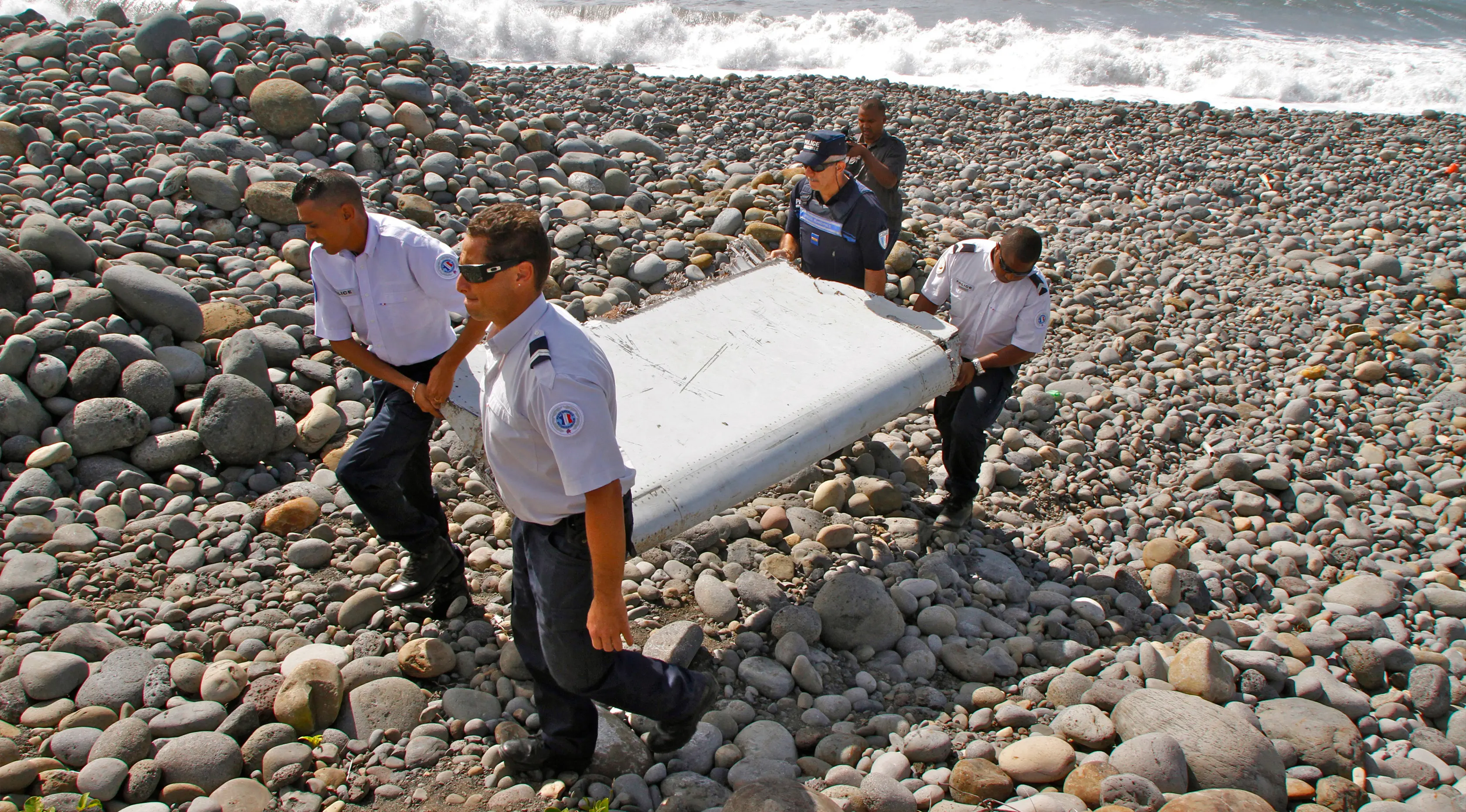 Foto ini diambil pada tanggal 29 Juli 2015, Polisi Perancis membawa potongan puing-puing dari pesawat yang diduga Malaysia Airlines MH370 di pantai Saint-Andre, Pulau Reunion. (AP Photo/Lucas Marie)