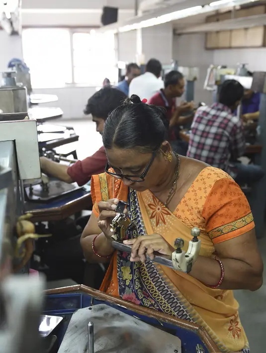 Seorang pekerja memeriksa batu berlian di bengkel pemotongan dan pemolesan berlian di Ahmedabad (23/7/2019). India merupakan pusat pemotongan dan pemolesan berlian terbesar di dunia. (AFP Photo/Sam Panthaky)