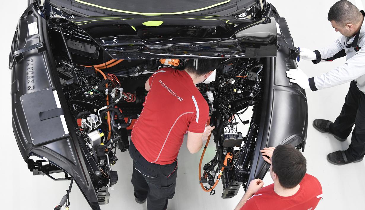 Mekanik melakukan pemasangan instalasi listrik mobil Porsche Taycan saat proses perakitan di pabrik perusahaan Porsche AG di Stuttgart, Jerman, Rabu (4/3/2020). Porsche Taycan merupakan mobil bertenaga listrik pertama  dari pembuat mobil mewah Jerman, Porsche AG. (AFP Photo/Thomas Kienzie)