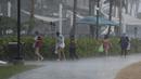 Warga berebut keluar dari guyuran hujan deras di Pantai Waikiki, Honolulu (6/12/2021). Badai kuat yang membawa angin kencang dan hujan yang sangat deras membanjiri jalan-jalan dan meruntuhkan kabel listrik dan cabang-cabang pohon di seluruh Hawaii. (AP Photo/Caleb Jones)