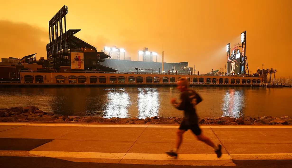 Seorang pria berlari di sepanjang McCovey Cove saat kabut asap menyelimuti langit di luar Oracle Park, San Francisco, Amerika Serikat, Rabu (9/9/2020). Kebakaran hutan di seluruh Barat mengakibatkan langit San Francisco hingga Seattle berwarna oranye yang menakutkan. (AP Photo/Tony Avelar)