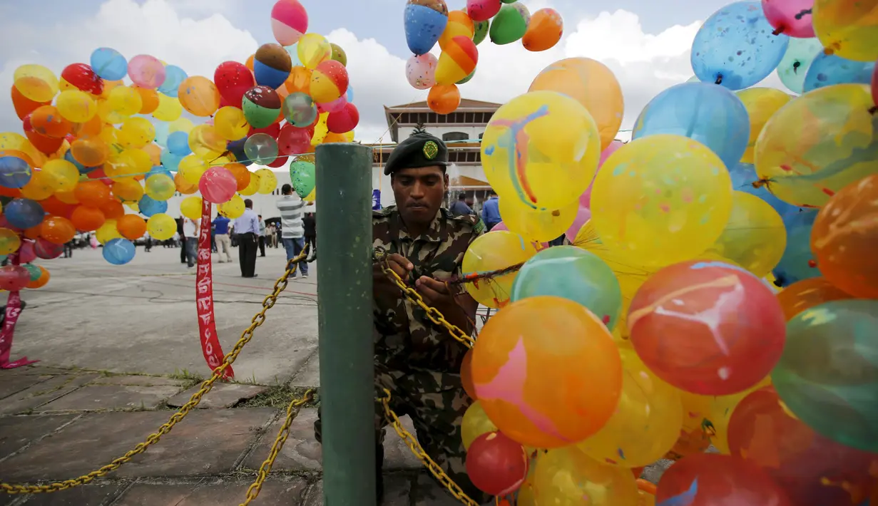Seorang tentara memasang balon di depan gedung parlemen jelang Presiden Ram Baran Yadav resmi mengesahkan konstitusi baru di Kathmandu, Nepal, Minggu (20/9/2015). Nepal akan mengadopsi piagam demokratis secara penuh. (REUTERS/Navesh Chitrakar)