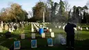 Pekerja membersihkan batu nisan kuburan Harefield di Hillingdon, Inggris, Rabu (23/11). Kuburan prajurit Australia & New Zealand yang tewas pada Perang Dunia I dicoret dengan graffiti kedua kalinya dalam 7 bulan terakhir di London.(REUTERS/Stefan Wermuth)
