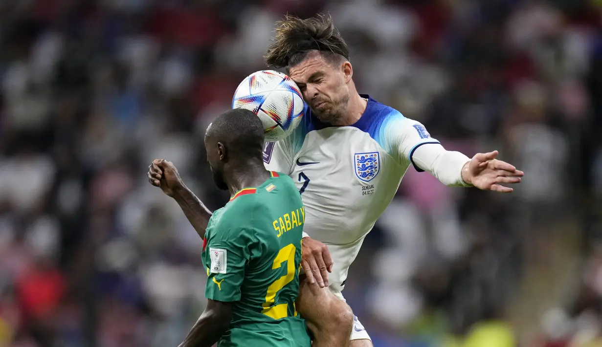 Gelandang Inggris Jack Grealish melompat untuk merebut bola dari bek Senegal Youssouf Sabali pada laga babak 16 besar Piala Dunia 2022 di Al Bayt Stadium, Senin (5/12/2022) dini hari WIB. Senegal mencoba mencari gol hiburan di sisa pertandingan, tetapi tak ada gol tambahan yang tercipta hingga peluit panjang berbunyi.  (AP Photo/Manu Fernandez)