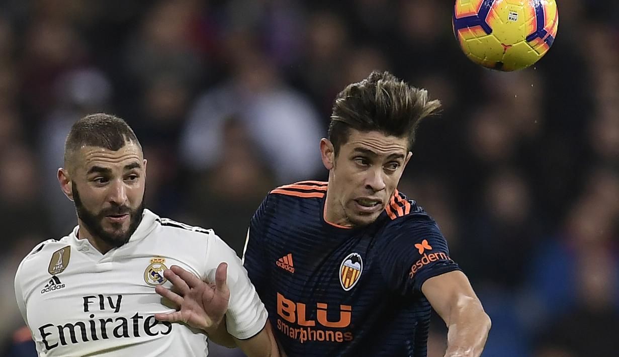 Striker Real Madrid, Karim Benzema, berebut bola dengan bek Valencia, Gabriel Paulista, pada laga La Liga di Stadion Santiago Bernabeu, Madrid, Sabtu (1/12). Madrid menang 2-0 atas Valencia. (AFP/Oscar Del Pozo)
