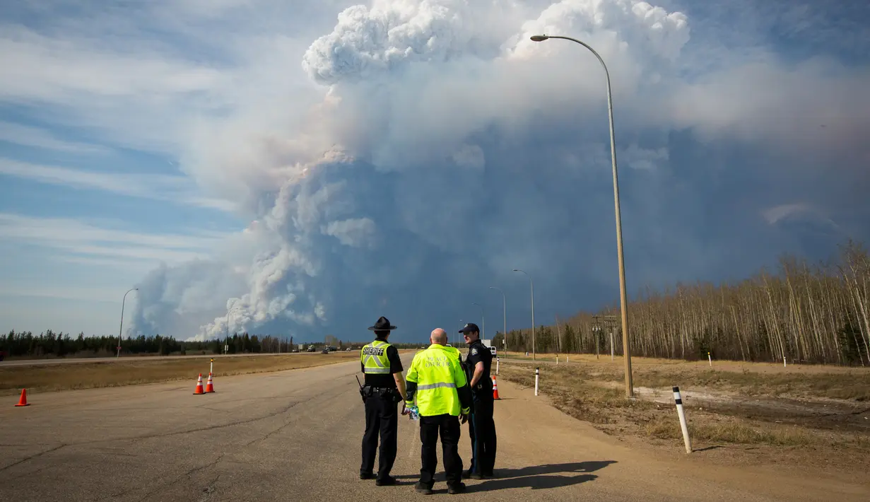 Petugas berjaga di kawasan dekat dari kepulan asap yang membakar hutan di wilayah Fort McMurray, Alberta, Kanda, 4 Mei 2016. Kebakaran ini merupakan yang terbesar kedua di wilayah tersebut dalam setahun. (REUTERS / Topher Seguin)