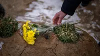 Seorang pria meletakkan bunga di makam seorang kerabatnya dalam upacara peringatan satu tahun dimulainya perang Rusia-Ukraina, di sebuah pemakaman di Bucha, Ukraina, Jumat, 24 Februari 2023. (AP Photo/Emilio Morenatti)