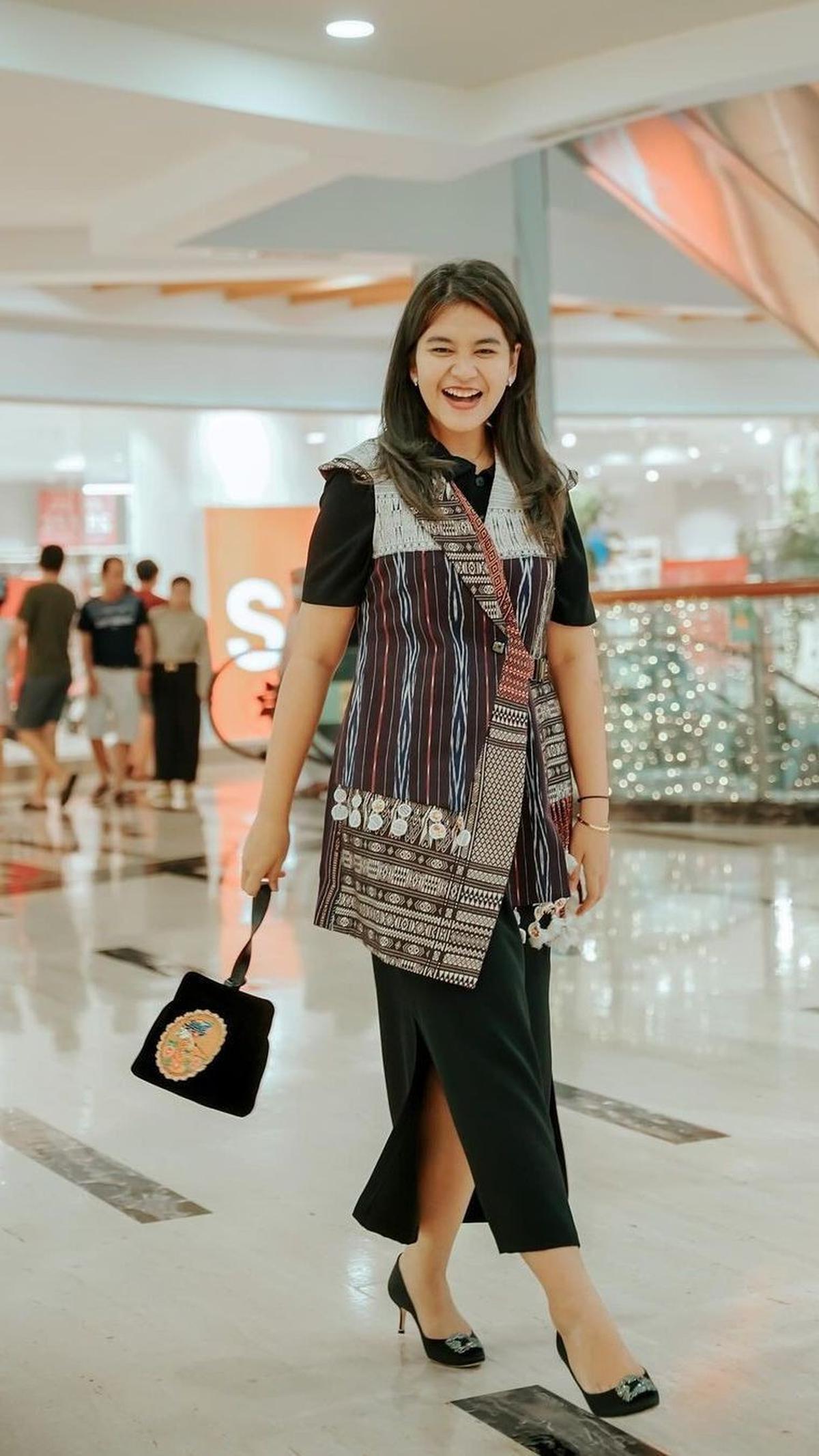 Dia pun melengkapi penampilan dengan tas kecil berwarna gelap yang ditenteng.