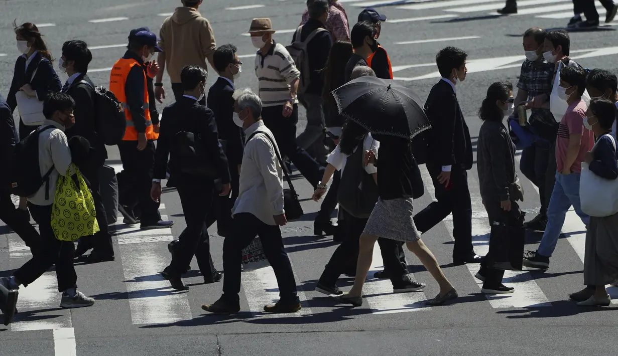 Orang-orang mengenakan masker untuk membantu mencegah penyebaran virus corona berjalan di sepanjang penyeberangan pejalan kaki di Tokyo (21/4/2021). Ibukota Jepang mengonfirmasi lebih dari 840 kasus virus corona baru pada hari Rabu. (AP Photo/Eugene Hoshiko)