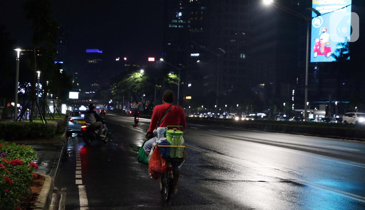 Pedagang kopi keliling melintas di jalan Jenderal Sudirman, Jakarta, Selasa (15/9/2020). Guna mengurangi pola penyebaran COVID-19, Pemda DKI Jakarta kembali menerapkan PSBB dengan membatasi aktivitas warga, perdagangan maupun perkantoran. (Liputan6.com/Helmi Fithriansyah)