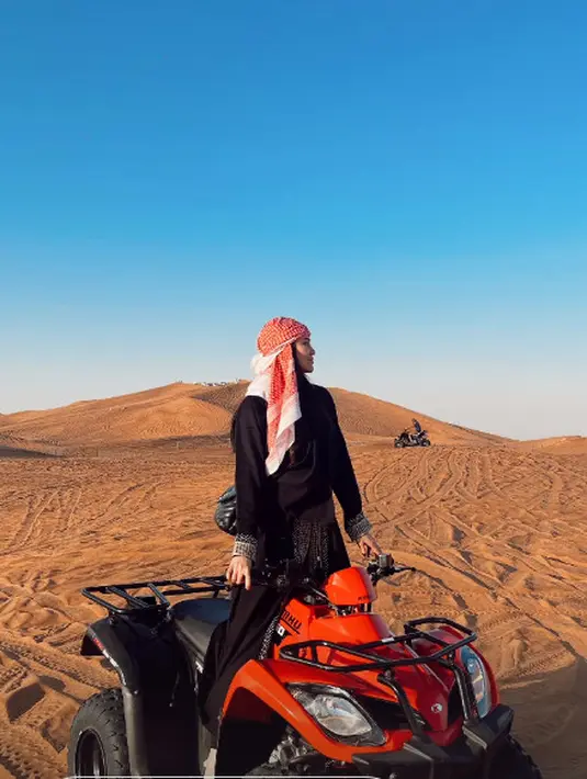 Meski kenakan gamis, Aaliyah tak ragu naiki ATV untuk menikmati indahnya padang pasir. Apalagi dipadukan dengan tas dari YSL dan sandal putih yang kontras dengan outfit serba hitam [@aaliyah.massaid]
