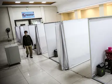 Petugas melintasi ruang isolasi mandiri pasien COVID-19 di Gelanggang Remaja Kecamatan Pademangan, Jakarta, Senin (28/9/2020). Sebanyak 30 bilik isolasi pasien Covid-19 disediakan dengan fasilitas tempat tidur, lemari, dan peralatan mandi. (Liputan6.com/Faizal Fanani)
