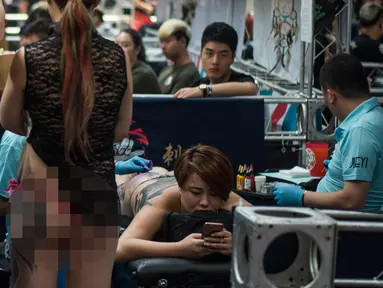Seorang wanita terbaring saat membuat tato dikakinya pada acara Langfang Internasional Tattoo di Hebei, China (29/5/2016). (AFP PHOTO / FRED Dufour)