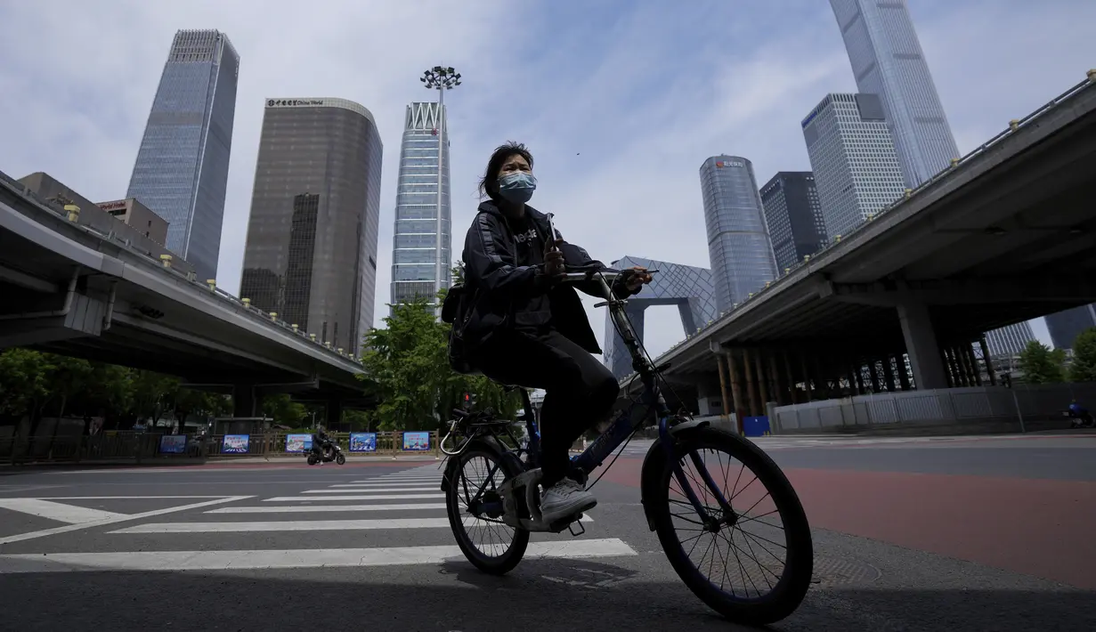 <p>Seorang perempuan mengenakan masker berkendara melintasi persimpangan yang tenang di kawasan pusat bisnis saat perintah bekerja dari rumah di distrik Chaoyang, Beijing, Rabu (11/5/2022). Shanghai pada Rabu menegaskan kembali akan mempertahankan pendekatan &ldquo;nol-COVID&rdquo; pengendalian pandemi, sehari setelah kepala Organisasi Kesehatan Dunia (WHO) menyatakan kebijakan itu tidak berkelanjutan dan mendesak China mengubah strategi. (AP Photo/Andy Wong)</p>