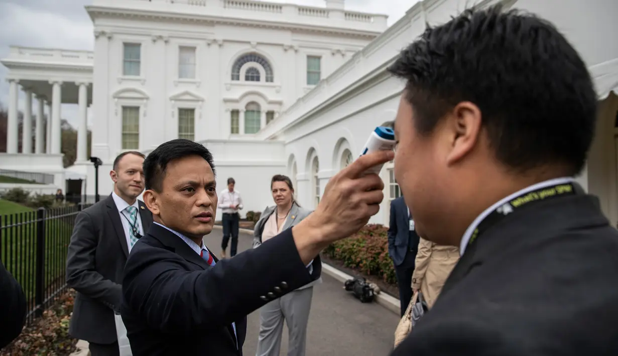 Anggota kantor dokter Gedung Putih memeriksa suhu jurnalis di luar Brady Press Briefing Room sebelum konferensi pers di Washington, Minggu (15/3/2020). Gedung Putih memberlakukan sejumlah langkah-langkah baru untuk melindungi Donald Trump dan stafnya dari virus Corona COVID-19. (AP/Alex Brandon)