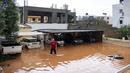 Warga berdiri di area parkir yang terendam banjir setelah hujan lebat di desa Malia, pulau Kreta, Yunani, Selasa (10/11/2020). Banjir besar di Pulau Kreta Yunani merusak jalan, membanjiri ratusan rumah, dan menyeret mobil ke laut di tengah hujan deras yang sedang berlangsung. (AP Photo/Harry Nakos)