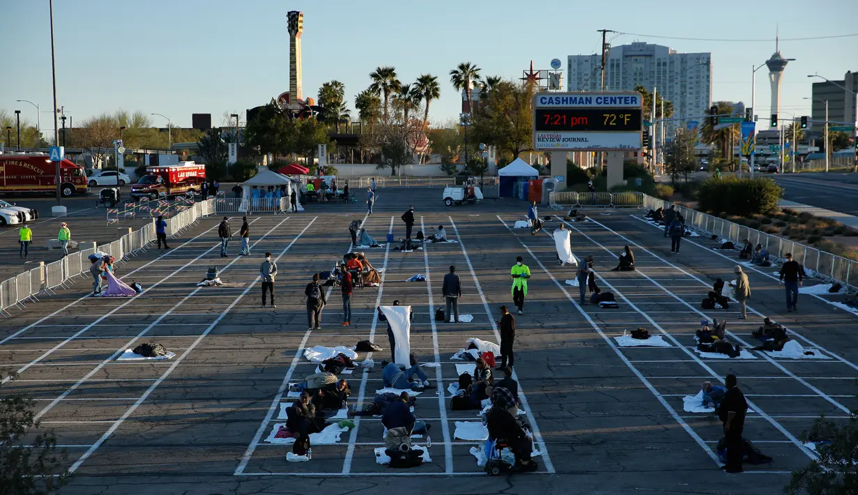 Tunawisma bersiap tidur di tempat-tempat yang ditandai dengan kotak-kotak untuk social distancing di lahan parkir di Las Vegas, Senin (30/3/2020). Lahan parkir itu menggantikan salah satu tempat penampungan lokal yang ditutup setelah seorang penghuni dinyatakan positif virus corona. (AP/John Locher)