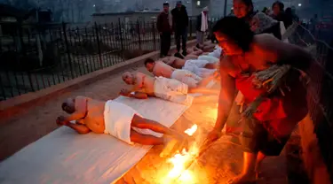 Umat Hindu Nepal berguling di tepi sungai Hanumante saat festival Madhav Narayan di Bhaktapur, Nepal (31/1). Ritual ini untuk persembahan kepada Dewi Swasthani dan Dewa Siwa. (AP Photo / Niranjan Shrestha)