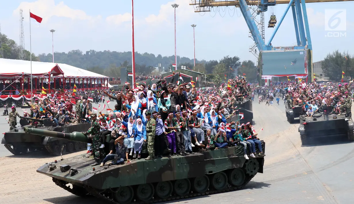 Warga bersama prajurit TNI berada di atas tank saat mengikuti defile pasukan dan kendaraan tempur pada peringatan HUT ke-72 TNI di Dermaga Indah Kiat, Cilegon, Kamis (5/10). HUT kali ini mengambil tema "Bersama Rakyat TNI Kuat" (Liputan6.com/Angga Yuniar)