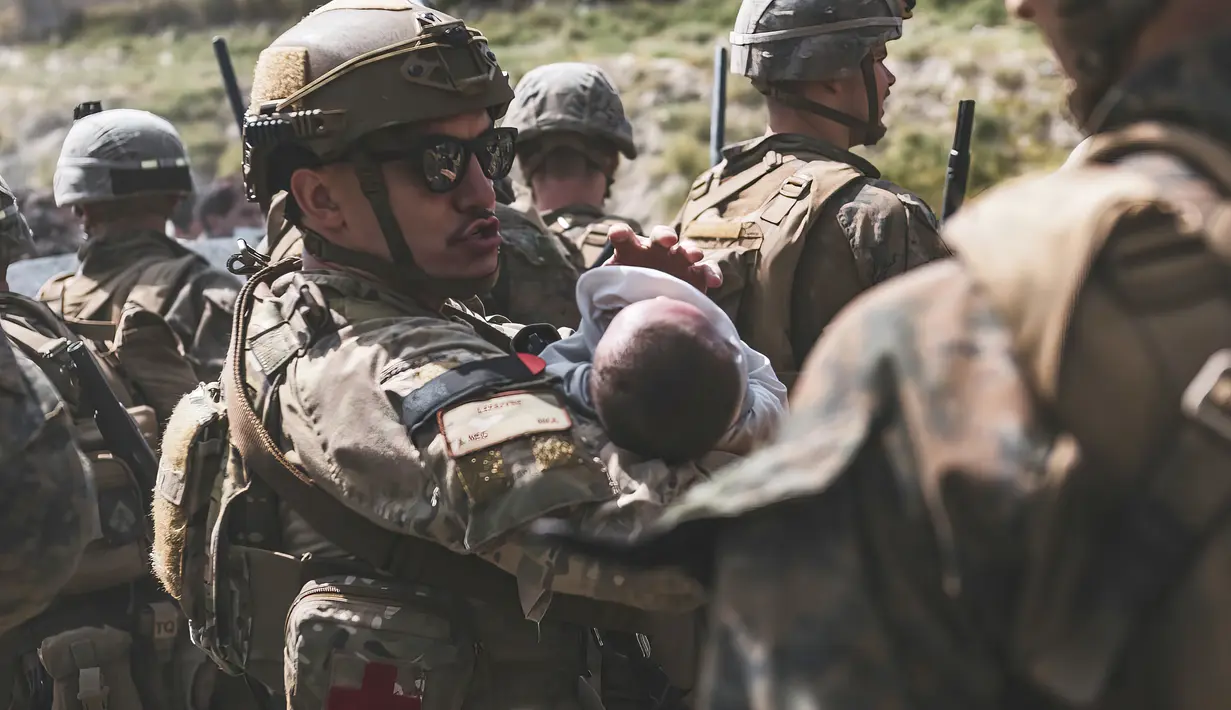 Seorang Penerbang menghibur seorang bayi selama mengungsi di Bandara Internasional Hamid Karzai di Kabul, Afghanistan, Jumat (20/8/2021). Hingga Jumat (20/8/2021), ribuan warga Afghanistan yang putus asa masih terus berkumpul di bandara Kabul. (Sgt. Isaiah Campbell/U.S. Marine Corps via AP)