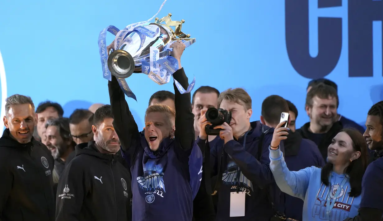 Pemain Manchester City Oleksandr Zinchenko mengangkat trofi di atas panggung disaksikan para penggemar saat parade kemenangan Liga Inggris di Manchester, Inggris, 23 Mei 2022. (AP Photo/Jon Super)