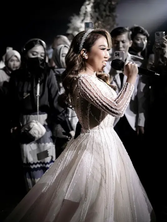 Kiky Saputri tampil menawan saat resepsi dalam balutan gaun putih rancangan Christie Basil. Detail salur pada bagian atas gaun-nya membuatnya tampak lebih ramping.