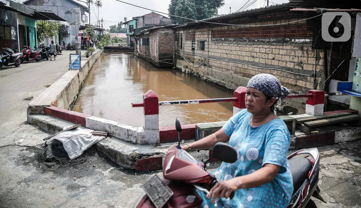 Pengendara motor melintas dekat bantaran Kali Induk Kramat Jati, Jakarta, Rabu(18/5/2022). Pemprov DKI Jakarta melalui Dinas Sumber Daya Air (SDA) berencana akan menormalisasi Kali Induk secara keseluruhan guna mencegah banjir yang melanda kawasan tersebut saat hujan deras mengguyur. (Liputan6.com/FaizaL Fanani)
