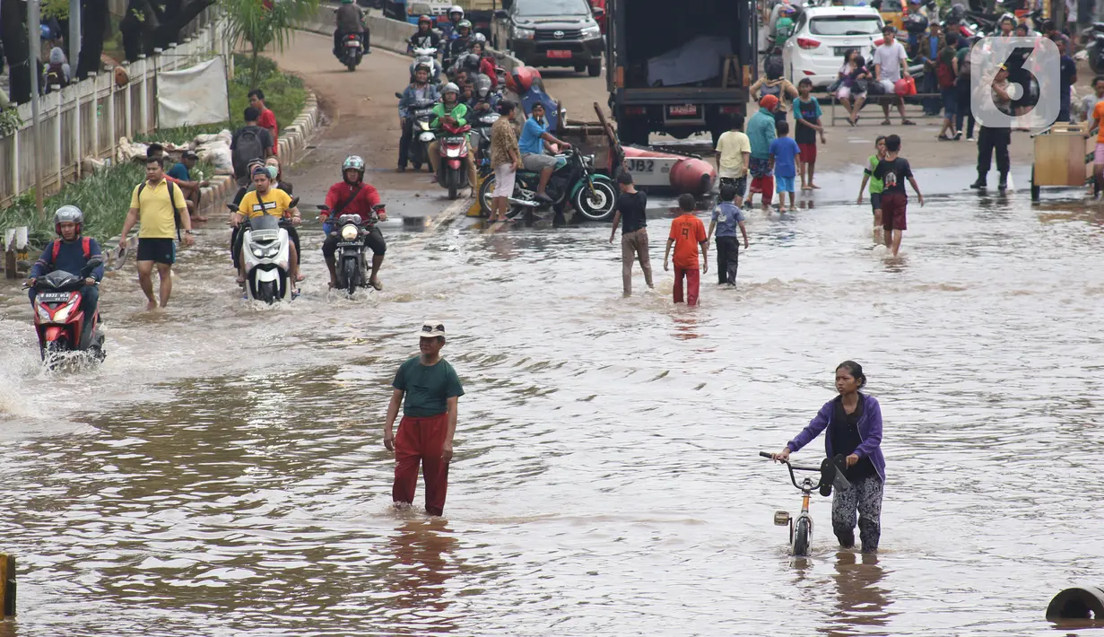 Pengendara dan pejalan kaki melewati perempatan Green Garden, Kedoya, Jakarta, Jumat (3/1/2020). Hingga hari ke-3, banjir masih menggenangi sekitar kawasan perempatan Green Garden, Kedoya akibatnya pengendara harus lebih waspada menghindari mesin kemasukan air. (Liputan6.com/Helmi Fithriansyah)